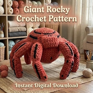 Puede incluir: Una araña grande de ganchillo de color coral con rayas negras, exhibida sobre una alfombra. El texto "Giant Rocky Crochet Pattern" y "Instant Digital Download" son visibles. El fondo incluye hilo y una estantería de madera.