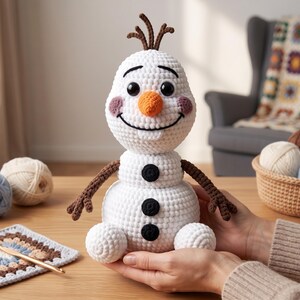 Pu&ograve; includere: Una bambola pupazzo di neve lavorata all'uncinetto in bianco con un naso arancione a forma di carota, occhi a bottone neri, un ampio sorriso ricamato, guance rosa e braccia marroni simili a ramoscelli. Il corpo presenta tre bottoni neri.
