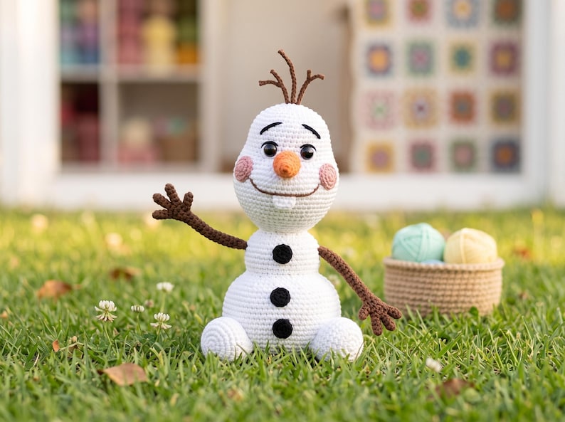 Pu&ograve; includere: Una bambola pupazzo di neve lavorata all'uncinetto in bianco con un naso arancione a forma di carota, occhi a bottone neri, un ampio sorriso ricamato e un singolo dente bianco. La figura ha braccia marroni a forma di ramoscello e guance rosa.