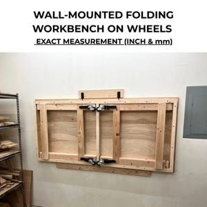 May include: A wall-mounted folding workbench on wheels. The workbench is made of light-colored wood and is mounted on a wall. The text "WALL-MOUNTED FOLDING WORKBENCH ON WHEELS EXACT MEASUREMENT (INCH & mm)" is at the top of the image.