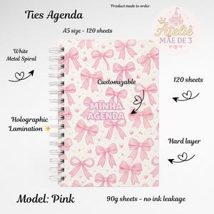 Pode incluir: Agenda rosa com encadernação em espiral de metal branco. A capa apresenta um padrão de laços e corações rosa, com o texto "MINHA AGENDA" no centro. A agenda é tamanho A5 com 120 folhas e laminação holográfica.