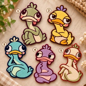 May include: Five embroidered patches featuring cartoon duck-like creatures with large eyes, sticking out tongues, and numbered one through five. The patches are colored sage green, yellow, teal, purple, and cream with dark brown or red outlines.