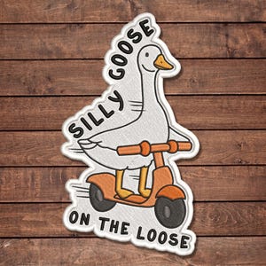 May include: An embroidered patch featuring a white goose with an orange beak riding an orange scooter. The text SILLY GOOSE ON THE LOOSE is stitched in black around the goose. The patch has a white border and a textured fabric appearance.