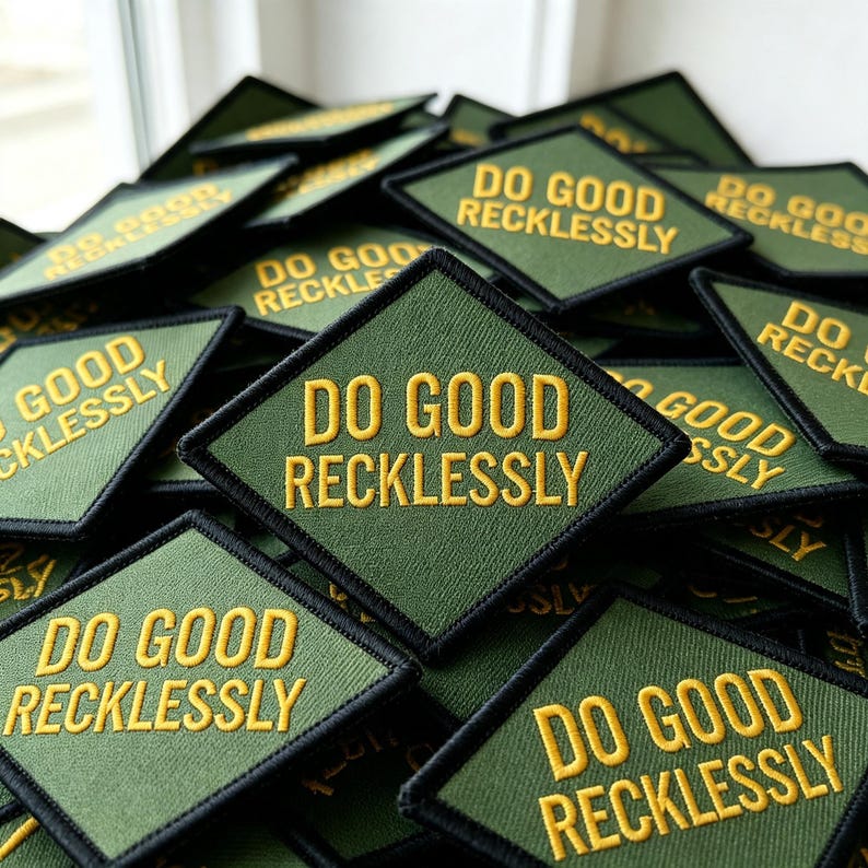 May include: A collection of diamond-shaped olive green fabric patches with black stitched borders. Each patch features the text DO GOOD RECKLESSLY embroidered in bold yellow capital letters, centered across two lines on the textured surface.
