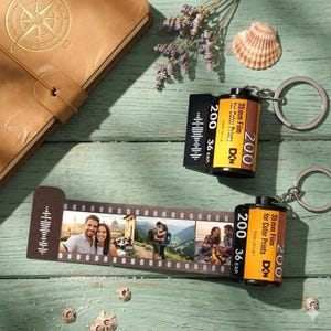 May include: Two film canister keychains and a photo strip with images of people. The film canisters are black and yellow with the text "200 36 EXP" and "35mm Film for Color Prints". The photo strip has four images.