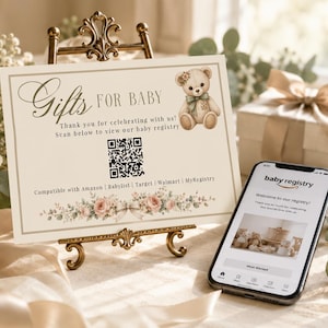 May include: A rectangular sign on a gold stand with the text Gifts FOR BABY, a teddy bear illustration, a QR code, and a floral border. The sign lists compatibility with Amazon, Babylist, Target, Walmart, and MyRegistry. A smartphone displays a baby registry page.