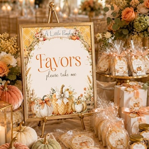 Peut inclure: Un panneau encadré d'or sur un trépied avec le texte A Little Pumpkin Favors please take one, orné d'illustrations de citrouilles, de fleurs et d'un fond à carreaux, entouré de citrouilles en velours et de cadeaux d'invités emballés.