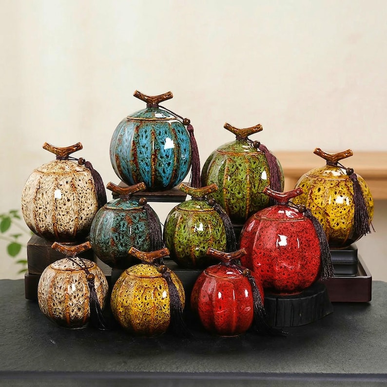 May include: A collection of ceramic jars in various colors, including blue, green, yellow, and red. Each jar has a rounded shape with a lid and a decorative tassel. The jars are arranged on a dark surface.