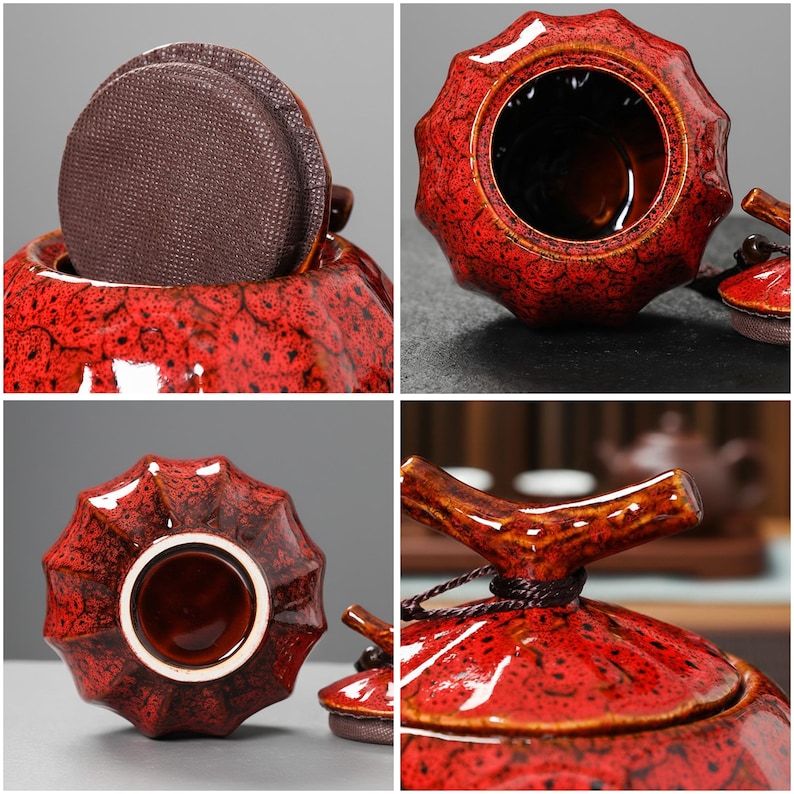May include: A red ceramic tea caddy with a textured, speckled finish. The caddy has a unique, ridged shape and a matching lid with a wooden handle. A brown, circular tea bag is visible inside.