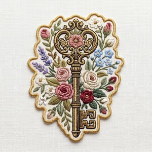 May include: Embroidered patch featuring a gold-colored key design surrounded by colorful flowers. The flowers include pink, red, white, and blue blooms, with green leaves. The patch has a gold border and is set against a white background.