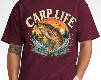 Puede incluir: Una camiseta de manga corta color granate con un gráfico de una carpa saltando sobre el agua, dos cañas de pescar cruzadas y el texto "CARP LIFE" en la parte superior y "LIVE FISH RELAX" en la inferior, sobre un fondo circular de atardecer.