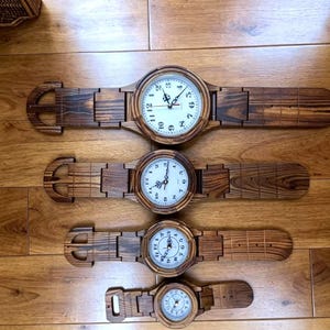 Puede incluir: Se muestran cuatro relojes de pulsera de madera con esferas blancas y números negros. Las correas del reloj son de la misma madera y tienen un diseño de hebilla. Los relojes están dispuestos en una fila, cada uno de un tamaño diferente.