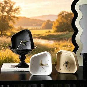 Puede incluir: Una colección de relojes modernos y minimalistas en negro, blanco y beige. Los relojes tienen manecillas doradas y marcadores de hora de puntos. Un reloj negro está en un cuenco negro. El texto "Nice to meet you" es visible.