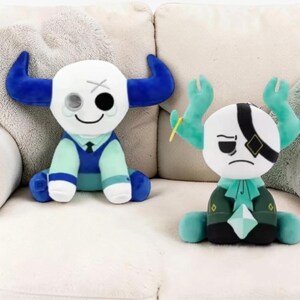 May include: Two plush toys with white heads, one with blue horns and the other with green horns. The first toy has a blue and teal outfit, and the second has a green and black outfit. Both toys have unique facial expressions.