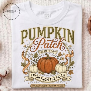 May include: A white t-shirt featuring a graphic print with the text PUMPKIN Patch FARM FRESH FRESH FROM THE PATCH LOCALLY GROWN AUTUMN PICKED. The design includes a large orange pumpkin, two smaller pumpkins, leaves, and a checkered ribbon border.