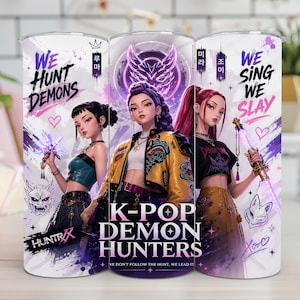 May include: A cylindrical tumbler featuring a graphic print of three anime-style characters with weapons. The design includes the text "WE HUNT DEMONS," "K-POP DEMON HUNTERS," and "WE SING WE SLAY" in purple and black, accented with hearts and masks.