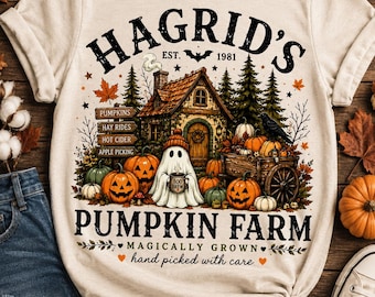 Op de afbeelding: Een crèmekleurig t-shirt met een afbeelding van een hut, een geest met een mok, pompoenen en een houten kar. De tekst luidt: HAGRID'S EST. 1981 PUMPKIN FARM, MAGICALLY GROWN, hand picked with care, PUMPKINS, HAY RIDES, HOT CIDER, APPLE PICKING.