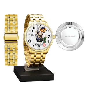 May include: Gold-plated wristwatch with a white face featuring a Polo bear in a golf outfit. The watch has a gold band and a separate band piece. The watch is displayed on a black stand, with a silver-toned back piece. The watch face displays the text "POLO RALPH LAUREN".