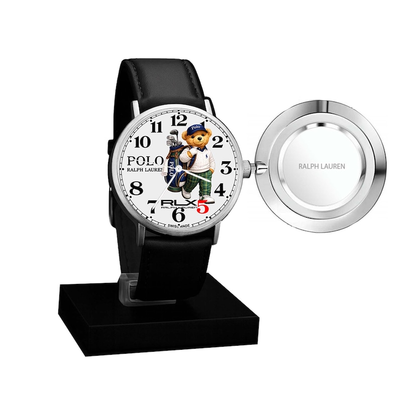 May include: A Polo Ralph Lauren wristwatch with a black leather strap and a white face. The watch face features a bear wearing a golf outfit. The watch is displayed on a black stand and includes a silver-coloured charging component.