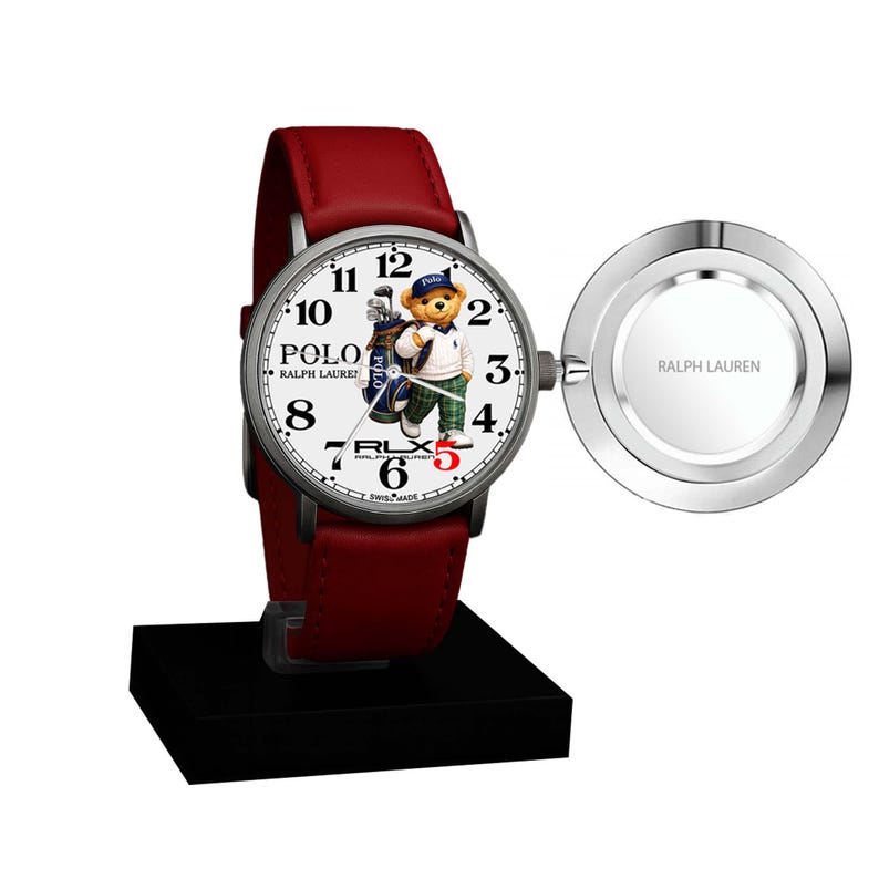 May include: A wristwatch with a red leather strap and a silver case. The watch face displays a bear in a golf outfit and the words "POLO RALPH LAUREN". A silver disc with "RALPH LAUREN" is attached to the watch.