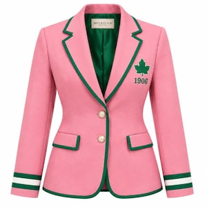 Könnte beinhalten: Ein rosafarbener Blazer mit dunkelgrüner Paspelierung an Revers, Saum und Taschen. Die Jacke hat zwei perlmuttartige Knöpfe, ein grünes Innenfutter und einen grünen Ahornblatt-Aufnäher über der Zahl 1906. Die Ärmel haben grüne und weiße Streifen.