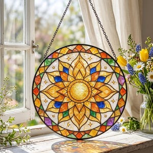 Peut inclure: Un capteur de soleil circulaire en vitrail présentant un motif de soleil jaune central entouré de motifs géométriques orange, bleus, verts et violets. La pièce inclut de petites étoiles et lunes et est suspendue par une chaîne en métal noir.