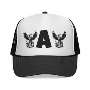 May include: A black and white trucker hat with a black brim and mesh back. The front panel displays the letter "A" flanked by two phoenix bird illustrations above flames. The hat is a stylish accessory.