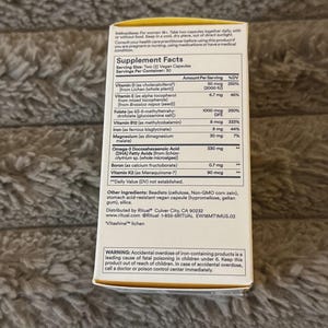 Puede incluir: Una caja de suplementos blanca y amarilla con informaci&oacute;n nutricional detallada, que incluye vitaminas D, E, B12 y hierro. La caja tambi&eacute;n enumera otros ingredientes y una advertencia sobre sobredosis accidental.