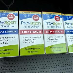 May include: Four boxes of Prevagen dietary supplement. The boxes are white, blue, and green, with text that reads "Prevagen For Your Brain." Two boxes are "Regular Strength" and two are "Extra Strength."
