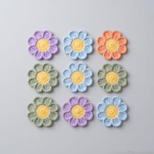 Puede incluir: Nueve apliques de flores de ganchillo dispuestos en una cuadrícula. Cada flor tiene un centro amarillo y pétalos en varios colores pastel: lavanda, azul claro, melocotón, verde y morado oscuro. Las flores son hechas a mano y parecen suaves.