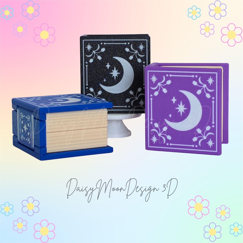 May include: Three decorative book-shaped boxes. One is blue, one is black, and one is purple. Each box features a crescent moon and star design. The boxes are on a pastel background with floral accents. The text "Daisy Moon Design 3D" is at the bottom.