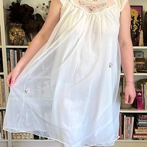 May include: A white ceramic mug with a black handle and the text "But First, Coffee" in a black, handwritten-style font. The mug is on a white surface.