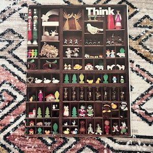 May include: A vintage wooden box filled with small wooden toys and figurines. The box has a label that reads "Think" and the date "November 1981".