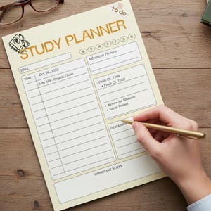 May include: A study planner with the title "STUDY PLANNER" in gold lettering. The planner is on a wooden desk with a cup of tea, glasses, a plant, and highlighters. A hand is writing on the planner with a gold pen.