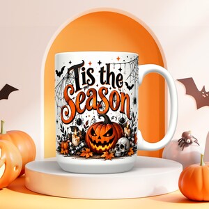 Peut inclure: Un mug en céramique blanche orné d'un motif sur le thème d'Halloween avec le texte 'Tis the Season' en noir et orange. Le design comprend une citrouille d'Halloween, un crâne, des toiles d'araignée, des chauves-souris et des feuilles d'automne.
