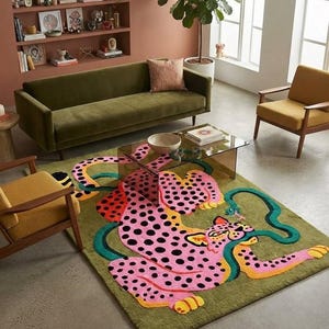 Peut inclure: Un tapis rectangulaire orn&eacute; d'un grand l&eacute;opard rose &agrave; pois noirs et d'un long serpent vert s'enroulant autour de son corps. Le tapis pr&eacute;sente un fond vert olive et est plac&eacute; sur un sol en b&eacute;ton devant un canap&eacute; en velours vert.
