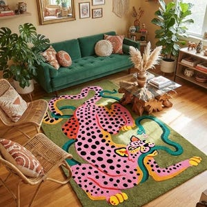 Peut inclure: Un tapis rectangulaire repr&eacute;sentant un grand l&eacute;opard rose stylis&eacute; avec des taches noires et des accents jaunes sur un fond vert olive uni. Le l&eacute;opard est repr&eacute;sent&eacute; en position allong&eacute;e avec une longue queue sinueuse qui traverse le tapis.