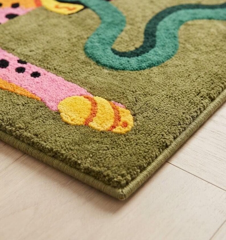 Peut inclure: Un tapis touffet&eacute; &agrave; fond vert olive pr&eacute;sentant un membre animal &agrave; motifs roses et orange avec des taches noires et une patte jaune, ainsi qu'une forme sinueuse vert fonc&eacute; rappelant un serpent avec une finition en relief textur&eacute;e.