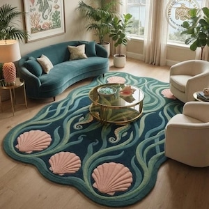 May include: A large, irregularly shaped area rug featuring a deep teal background with flowing light green seaweed patterns, three prominent pink seashells, and two seahorses. The rug has a soft, tufted texture and a distinct, organic, wavy border.