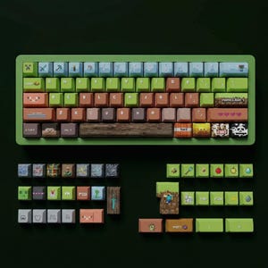 May include: A green mechanical keyboard with custom keycaps featuring a Minecraft theme. The keycaps are various colors and depict pixelated images of blocks, characters, and icons from the game. Additional keycaps are displayed below the keyboard.
