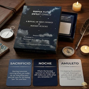 Op de afbeelding: Een donkerblauwe doos met de tekst "PEPPER PAPER SWEET CHILLI" en "A RITUAL OF DEEP DESIRES & HONEST ECHOES." De set bevat kaarten met Spaanse tekst, een kompas, een veerkiel en brandende kaarsen.