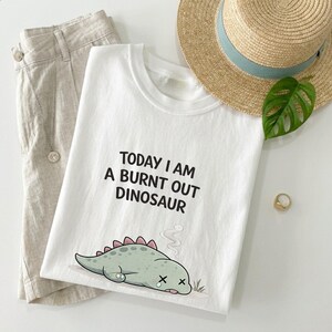 Low energy dinosaur shirt styled on neutral background with cozy aesthetic elements
Burnout gift idea shirt with funny dinosaur graphic shown in relaxed everyday outfit mockup