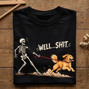 May include: A black t-shirt featuring a graphic of a skeleton being pulled by a golden-coloured dog on a red lead. The skeleton is missing its lower arm, and the text "WELL... SHIT." is printed in white above the dog, which is kicking up dust.