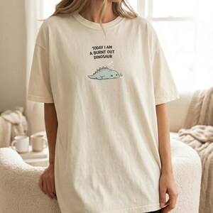 Funny tired dinosaur shirt for introverts styled in minimal neutral mockup scene