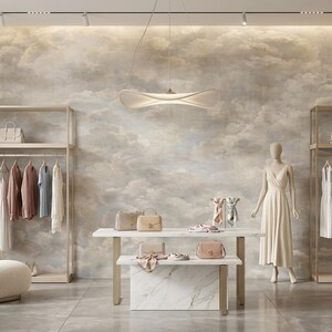 Può includere: Interno di una boutique con espositori, un tavolo espositivo e un manichino. Le pareti presentano un murale di nuvole. Vengono esposte varie borse e sciarpe. L'illuminazione è soffusa e calda.