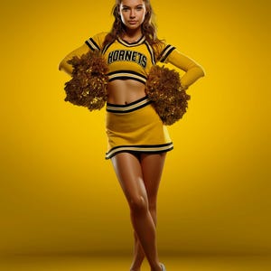 Puede incluir: Una joven con un uniforme de animadora amarillo y negro con la palabra "Hornets" en la parte superior. Sostiene pompones dorados y lleva zapatillas grises. El fondo es amarillo liso. El texto en la parte superior derecha dice "Staci Dillard 2026".