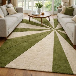 May include: A green and cream-coloured area rug with a sunburst design. The rug is placed in a living room setting, with two light-coloured sofas and a round wooden coffee table. The rug's design radiates from a central point.