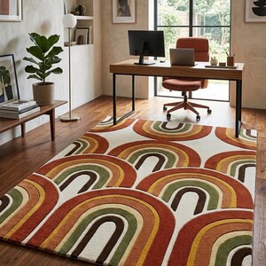 May include: A rectangular area rug with a repeating rainbow pattern in shades of orange, yellow, green, and brown on a cream background. The rug is placed on a hardwood floor in a home office setting.