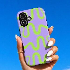 May include: A rectangular smartphone case featuring a light purple background with a repeating pattern of bright lime green wavy lines. The case has a black camera module cutout in the upper left corner with two circular lens openings and a flash.