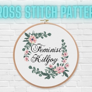 May include: Cross stitch pattern featuring a floral wreath and the text "Feminist Killjoy".